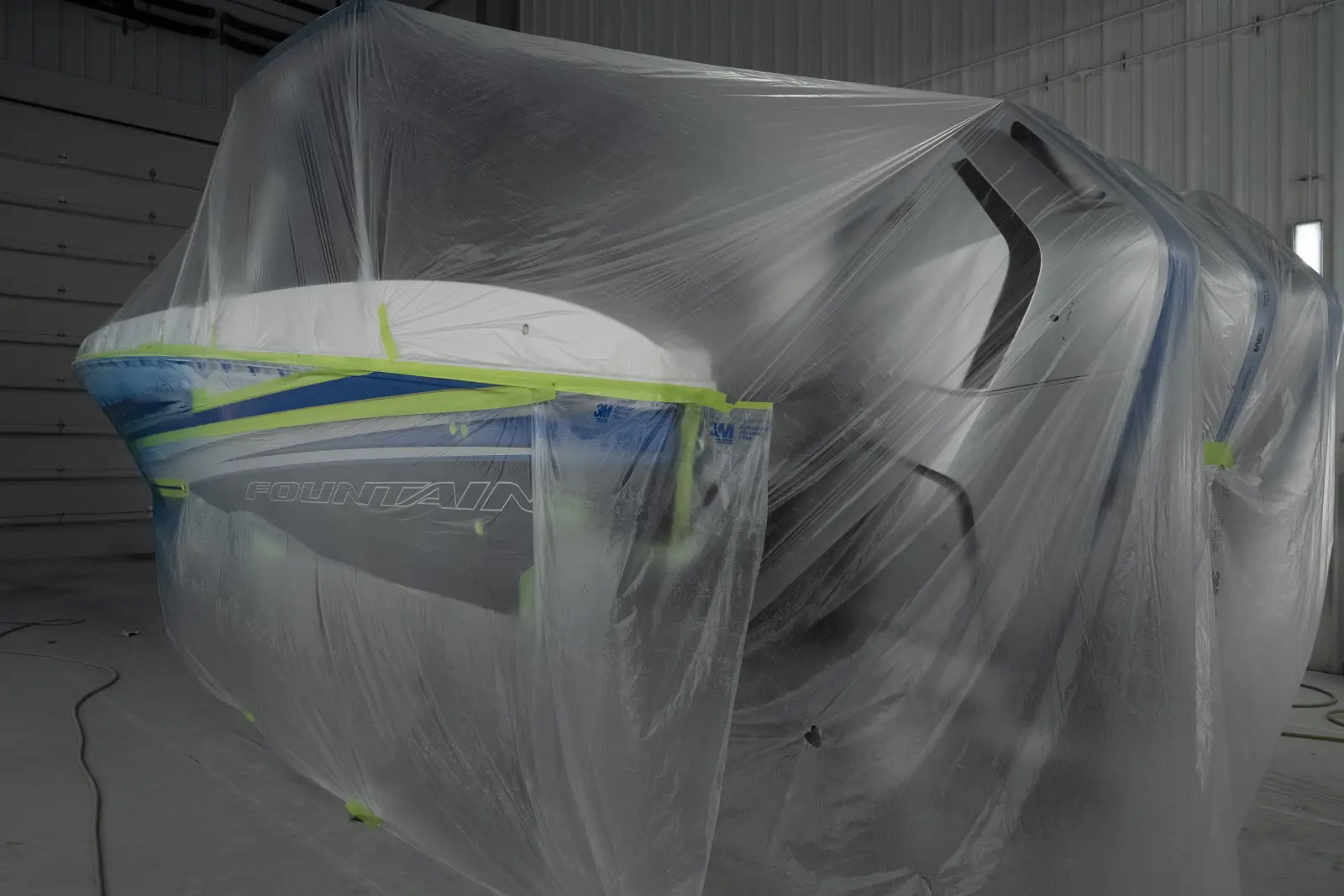 A boat hull masked in plastic and tape for painting in the Big Thunder Marine paint booth
